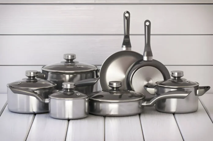 A set of stainless steel cookware including pots and pans with lids, displayed against a wooden backdrop